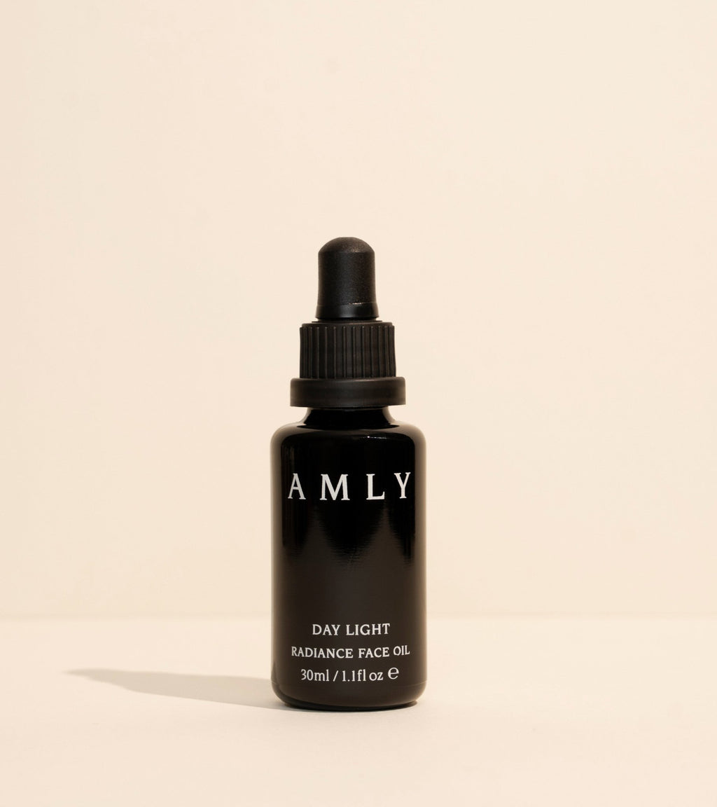 AMLY Day Light Face Oil in a black glass dropper bottle on a beige background